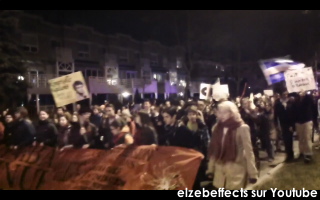 photo: la marche de nuit vue de face. Bannière rouge illisible; pancarte jaune; drapeau du Québec; plusieurs jeunes femmes