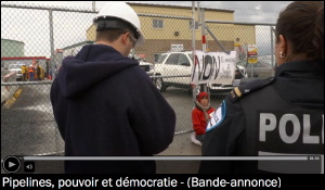 Image d'accueil de la bande-annonce, tirée du site de l'ONF. Un « foreman » et une policière regarde une jeune personne qui s'est enchaînée à une entrée clôturée.