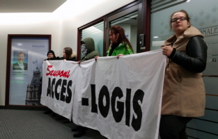 Photo : cinq personnes tiennent une banderole « Sauvons ACCÈS-LOGIS » dans le bureau du député. On voit d'ailleurs la photo de M. Blais sur le mur.