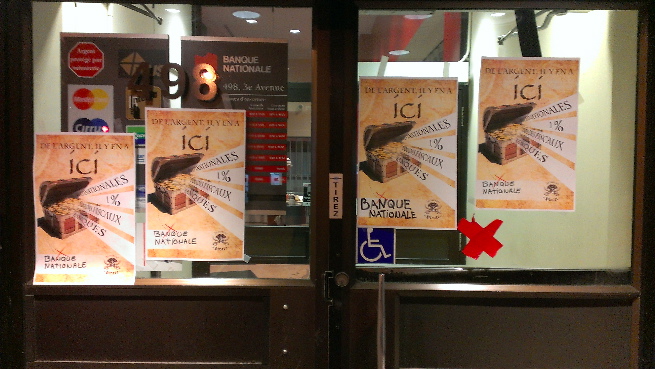 Photo : deux portes modernes vitrées de la Banque nationale avec 4 affiches pour l'action du 16 mars 2016.