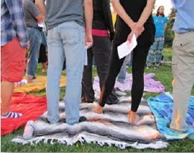 Photo : six personnes pieds nus sur debouts sur des couvertures. On voit seulement leurs jambes et bas du corps.