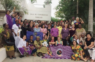 Photo de groupe au Mozambique: environ 40 femmes d'apparences très variées, plusieurs portent du mauve comme le drapeau de la MMF. On reconnaît d'ailleurs Émilia Castro de Québec (CSN).