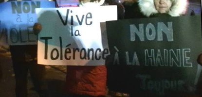 Photo de trois pancartes tenues par des personnes dont on voit seulement les manteaux d'hiver.  Non à la violence - Vive la tolérance - Non à la haine.