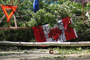 Photo, sur fond d'une barricade d'arbres feuillus de forêt boréale : un drapeau canadien est accroché à l'envers avec les mots « This is indigenous land ».