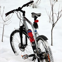 Photo d'un vélo de montagne qui se tient seul dans un tas de neige très blanche.