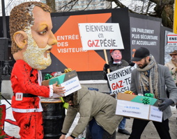 Photo : marionnette géante du premier ministre Couillard portant un habit de Père Noël taché d'une substance noire (pétrole). Des gens transportent des boîtes avec des titres dessus représentant à qui Couillard fait des cadeaux. Un faux ministre derrière tient une affiche « Bienvenue en GAZpésie ».