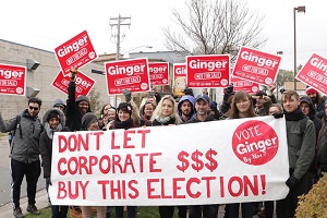 Photo : manif pour la campagne de Gingeré  Plusieurs jeunes, de genres variés, avec des pancartes roses. Bannière se lisant Don't let corporate money buy this election!