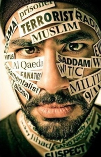 Portait photo de près d'un homme d'environ trente ans, mais dont le visage est couvert d'étiquettes : terroriste, radical, Al Qaeda, fondamentaliste, etc.