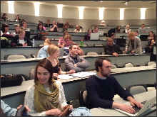 Photo de la salle de classe principale, un peu comme un auditorium, avec de beaux bureaux gris: il y a plus de 30 personnes, dont plusieurs jeunes hommes (indiquant donc une mixité).