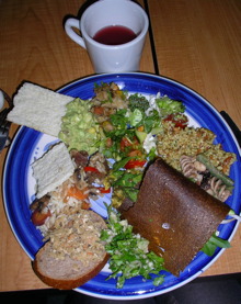 Photo d'un beau repas dans une assiette : un mélange de pains bruns, de salades, etc.
