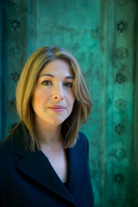 Photo: Ed Kashi - naomiklein.org - Naomi, en veston bleu-noir, regardant sereinement la caméra. Derrière, un fond verdâtre.