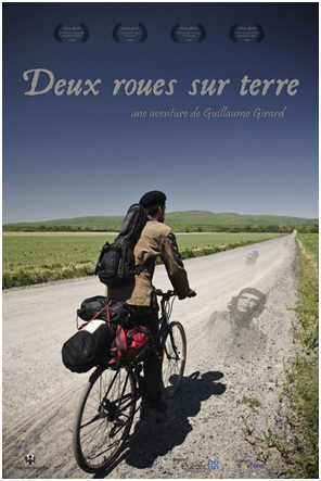 affiche du film : vue de dos, un jeune homme en vélo, avec quelques bagages, un béret noir, sur une longue route sur des plaines vertes. Superposé sur la route, on voit le visage iconique de Che guevara.