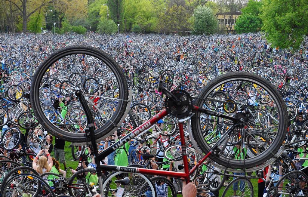 Photo : un vélo tenu en envers les pneux vers le ciel, devant une foule vraiment énorme et dense qui fait de même.