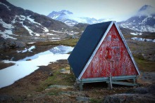 Une petite cabane triangulaire sur un flanc de montagne glaciale à perte de vue.