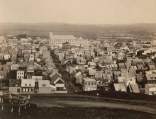 Photo ancienne du quartier Saint-Sauveur : rues de terre, surtout des maisons très près une de l'autre. On voit une rue principale (de terre). Une église au loin.