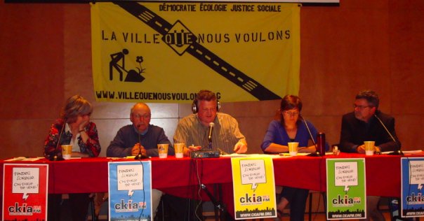 Photo des quatre panélistes et l'animateur : Winnie Frohn, Réjean Lemoine, Véronique Laflamme, Jean Bousquet, Marc De Koninck. Affiches colorées de CKIA. Grande bannière jaune de style construction : « démocratie écologie justice sociale ».