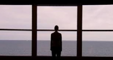 Capture d'écran officiel : une jeune femme, de dos aux cheveux très courts, devant trois énormes fenêtres donnant sur la mer à perte de vue.