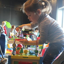 Photo : petite fille [env. 2-3 ans] concentrée sur un jeu intriguant.