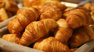 Photo de plusieurs petits croissants (pain) empilés dans un panier.