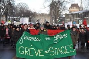 Photo : manif étudiante, à Québec, près des fortifications historiques. Vue de face, bannière verte « femmes en grève - grève des stages ».