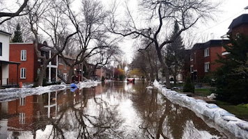 Photo : rue innondée d'eau, aussi bordée de neige, entre des blocs appartement.