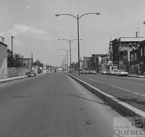 Photo en noir/blanc du boulevard Charest dans la partie du quartier Saint-Sauveur : quelques habituations carrées, mais on voit surtout le béton et les lampadaires doubles.