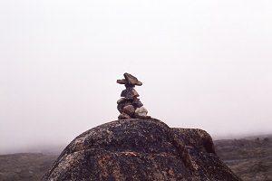 Photo d'un petit inukshuk, soit un petit bonhomme de pierres sur une grosse pierre. Utilisés comme marqueurs de chemin, etc.