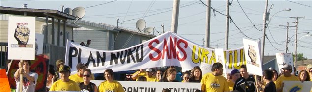 Photo du devant d'une manif de la communauté des Cris de Mistissini au Québec: bannière Plan Nord sans Uranium. Les gens portent des t-shirt jaune.