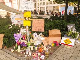 Photo : des fleurs, cartons portant des messages, sur le Parvis de l'église pour dénoncer la mort de Guy Blouin.