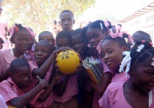 Photo : groupe d'une dizaine d'enfants noirs, portant des vêtements roses, posent pour la caméra, les mains sur un ballon au centre.
