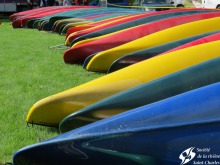 Photo : la pointe d'environ 20 kayaks de couleurs différentes sur un gazon très vert.