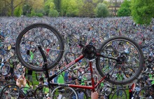 Photo : un vélo tenu en envers les pneux vers le ciel, devant une foule vraiment énorme et dense qui fait de même.